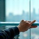 Cleaner squeegeeing window pane overlooking Manchester skyline
